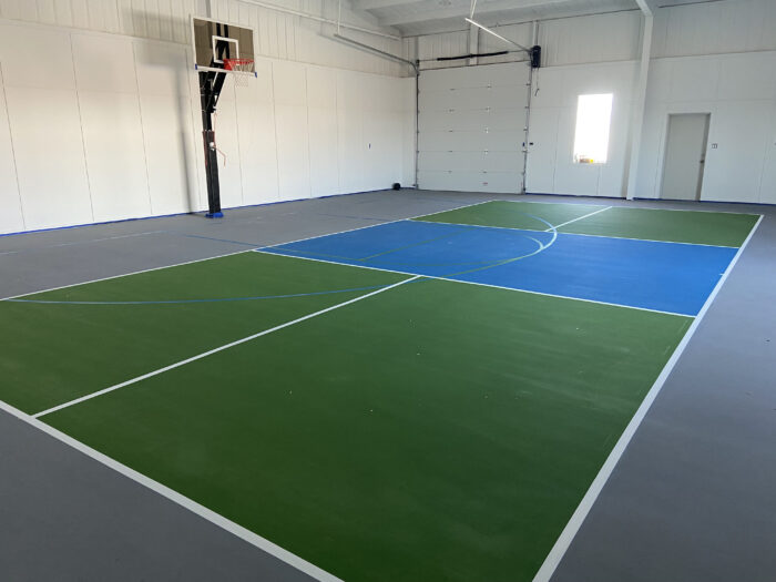 An image of a pickleball court with a basketball hoop off to the side.